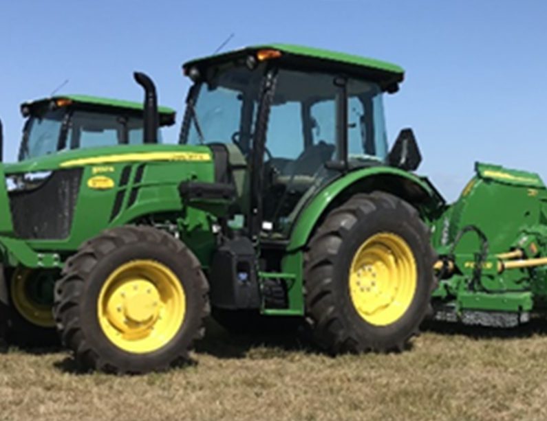 Green tractors are parked in a lush field, showcasing their vibrant color against the natural landscape