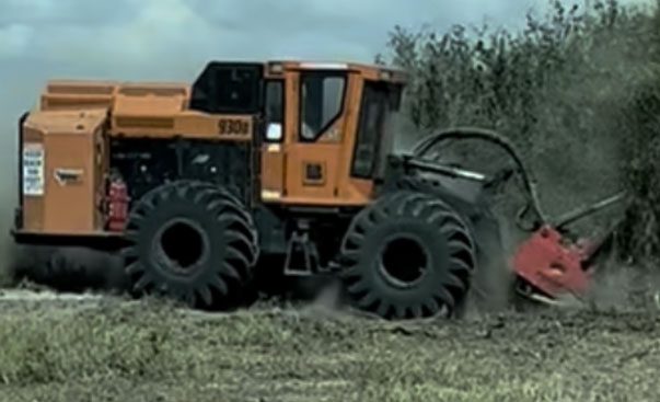 A large tractor navigates through a dirt path, showcasing its robust design and agricultural utility in action